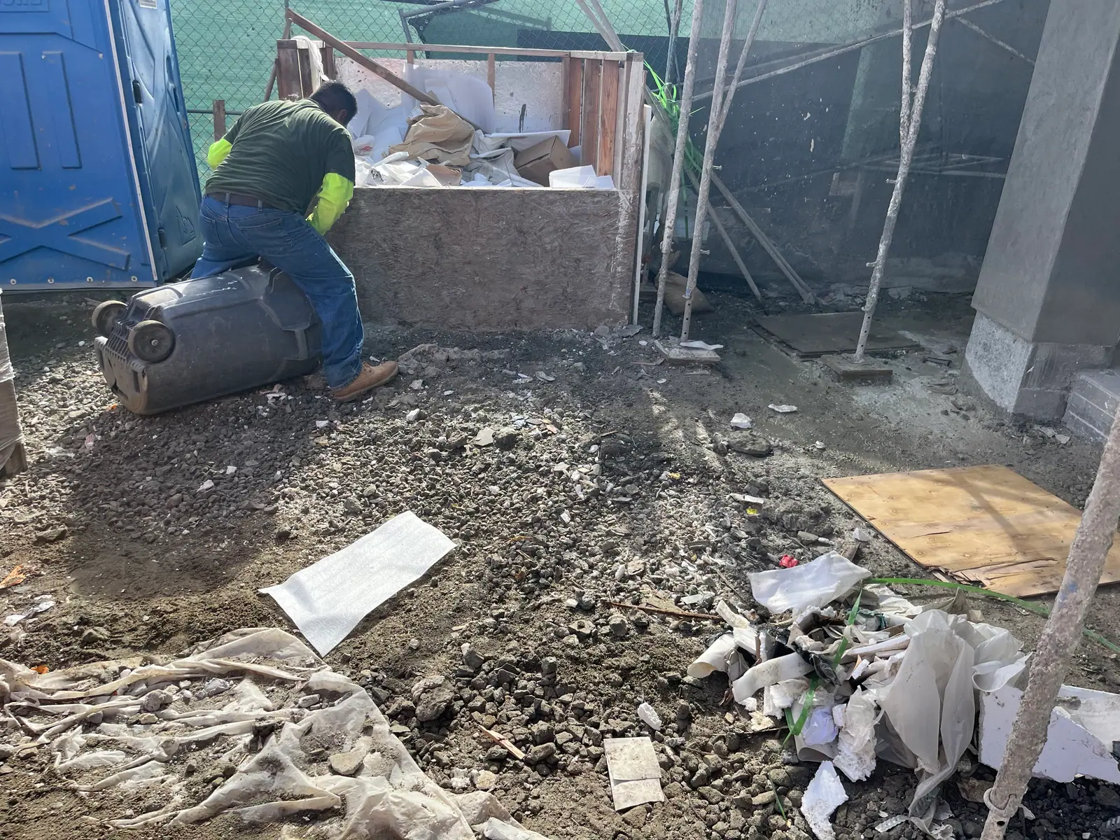 Crew member loading jobsite debris into a plywood debris box
